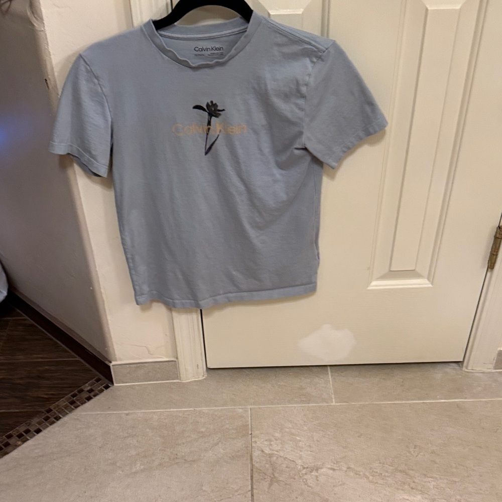 Calvin Klein Sky Blue Tee with Gold Logo with black flower.  100% cotton
